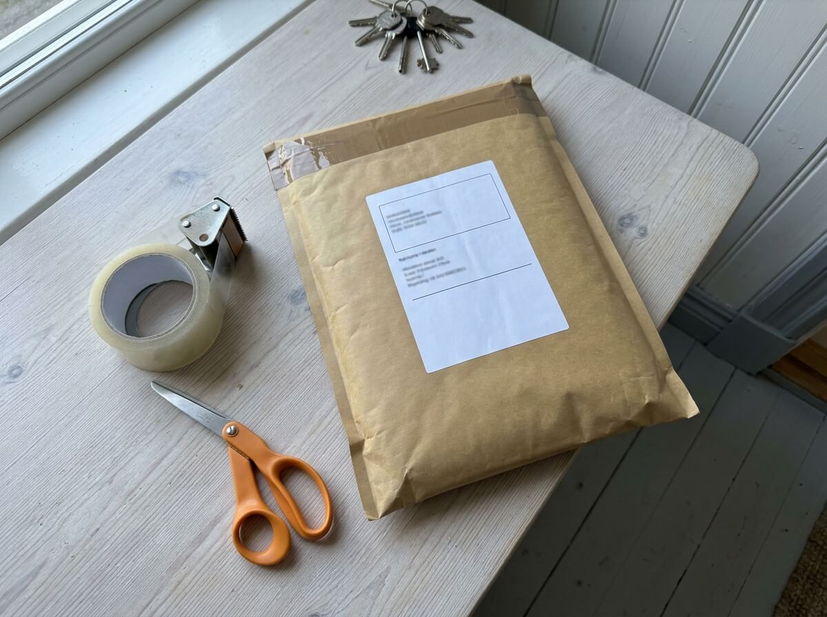 Färdigpackat brunt paket med adresslapp, tejp och sax på ett bord, redo att skickas